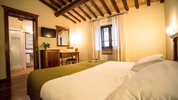 Ein Hotelzimmer mit Bett, Schreibtisch, Stuhl, Spiegel und einem Fenster mit Vorhängen.