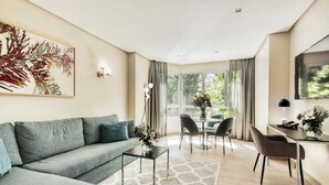 Ein modernes Wohnzimmer mit grauem Sofa, Couchtisch und einem Essbereich mit Stühlen und Tisch.