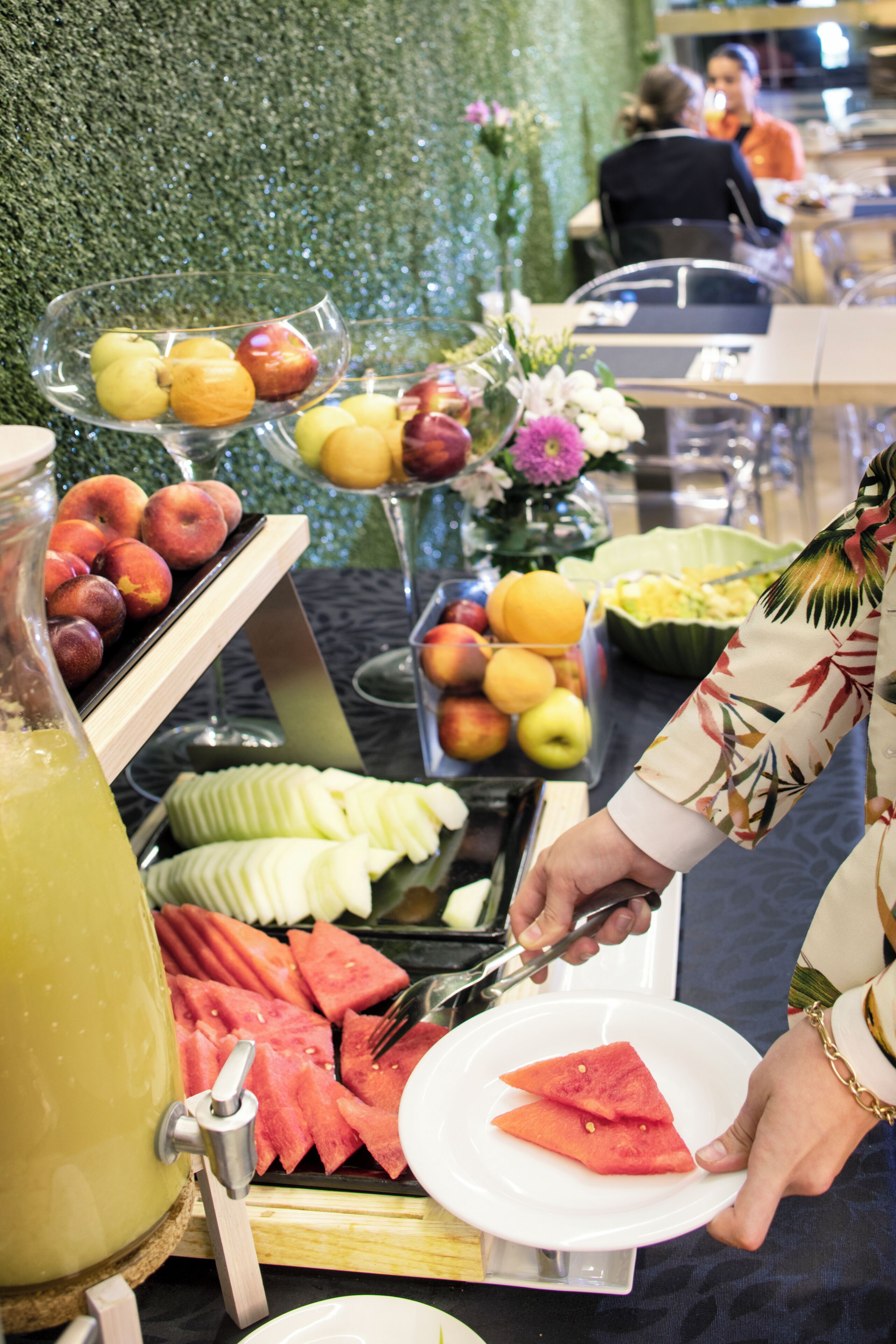 A buffet with various fruits and a watermelon slicer.