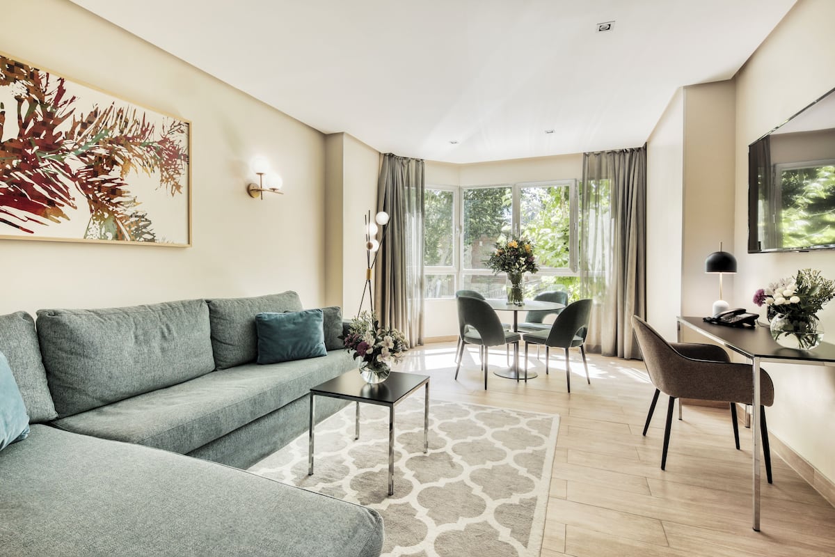 Een moderne woonkamer met een grijze bank, een glazen salontafel, en een eethoek met een tafel en stoelen.