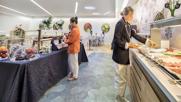 Un espace buffet proposant divers plats et une personne chargée de servir les aliments.