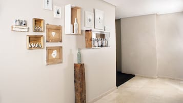 A hallway with a tiled floor, wooden display shelves, and various framed artworks.
