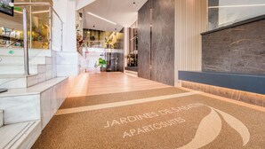 Eine moderne Hotelhalle mit Marmorboden, einer Rezeption und einer Treppe zu einer oberen Ebene.