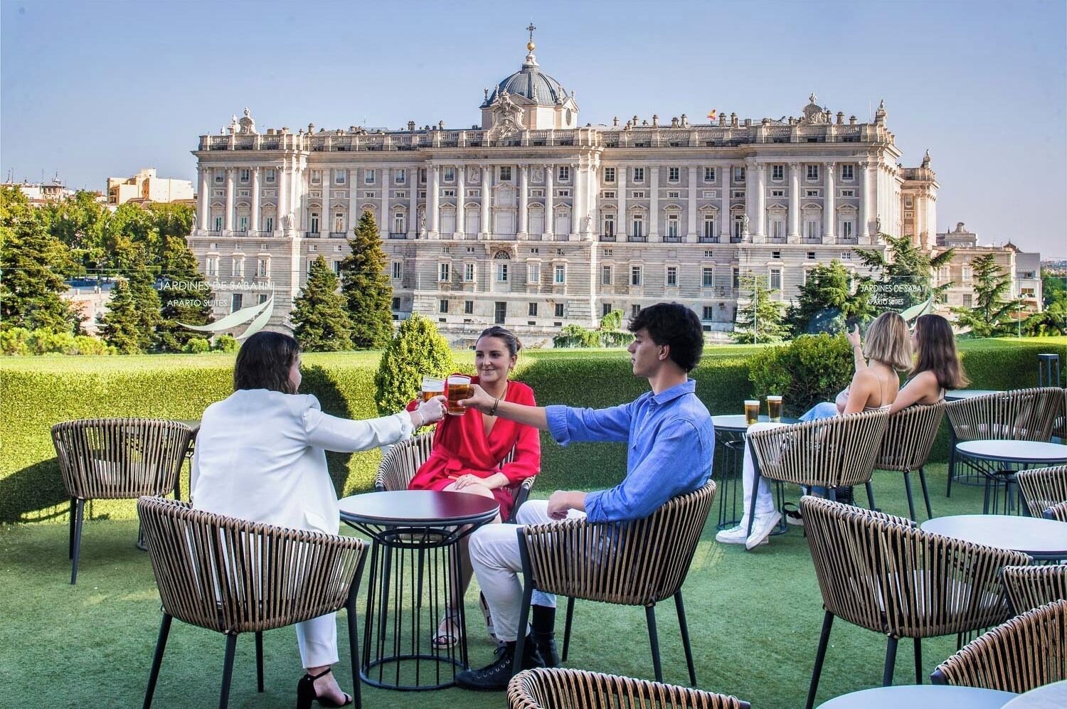 A group of people toasting at an outdoor café with a historic building in the background.