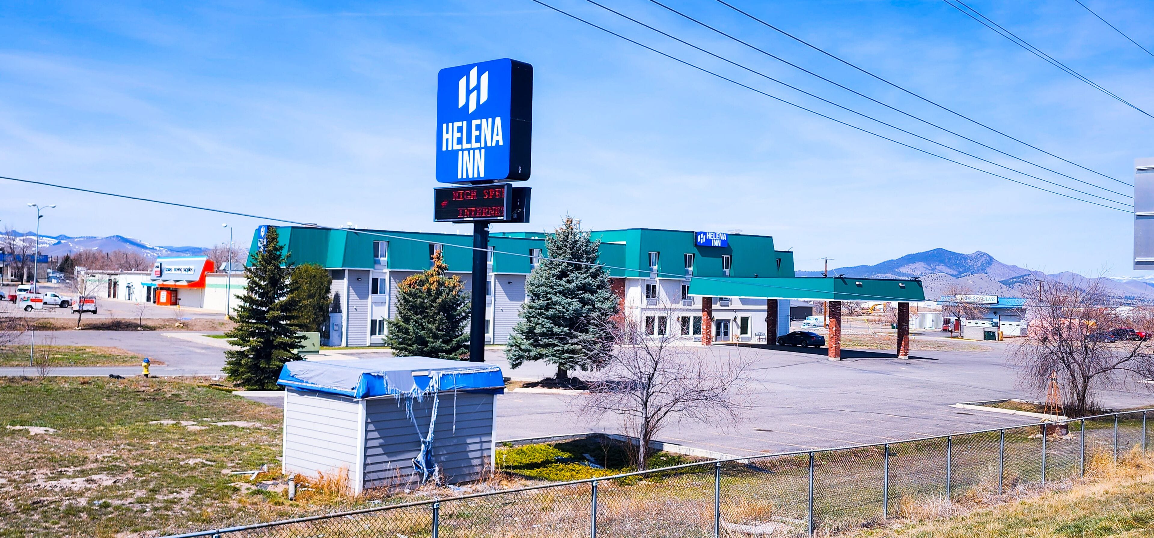 A Helena Inn with a large sign, a parking lot, and a mountainous backdrop.