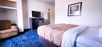 Una habitación de hotel con cama, televisión, escritorio y silla, además de un microondas.
