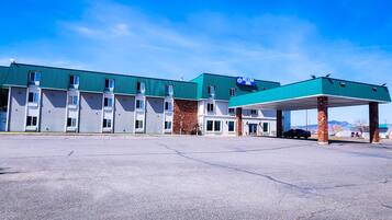 A motel with a green roof and a covered parking area.