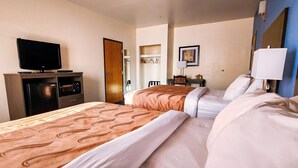 A hotel room with a bed, a television on a stand, a wardrobe, and a mirror on the wall.