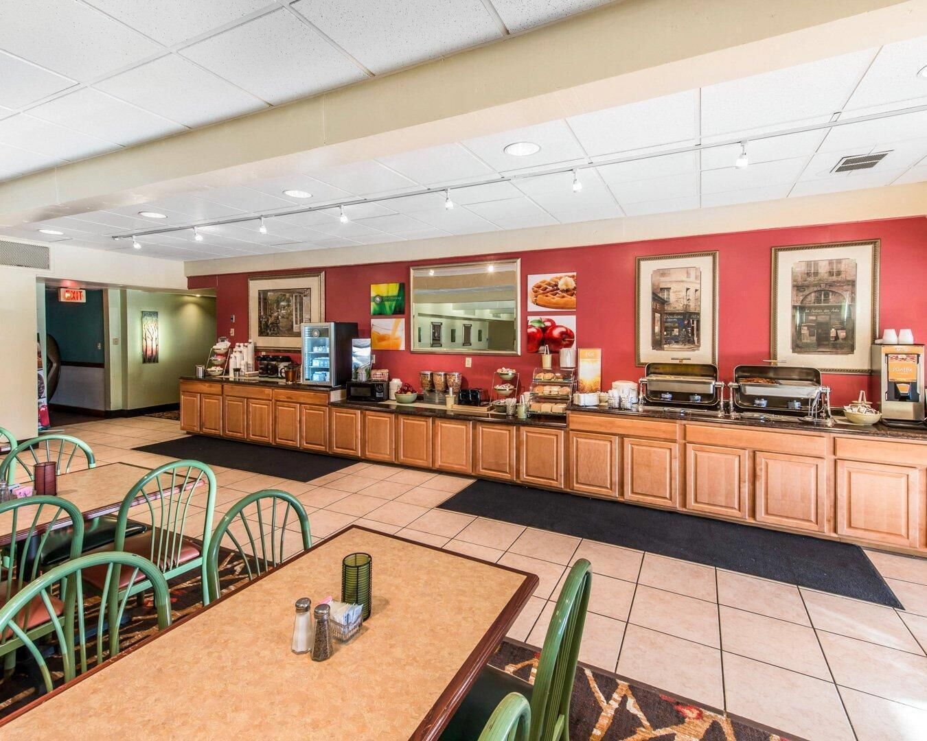 A hotel breakfast area with a long counter, seating area, and exit sign.
