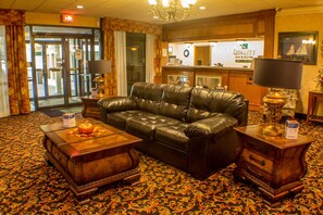 A lobby with a leather sofa, wooden coffee table, and a reception desk. - Quality Inn & Suites Erie near Casino (Erie)