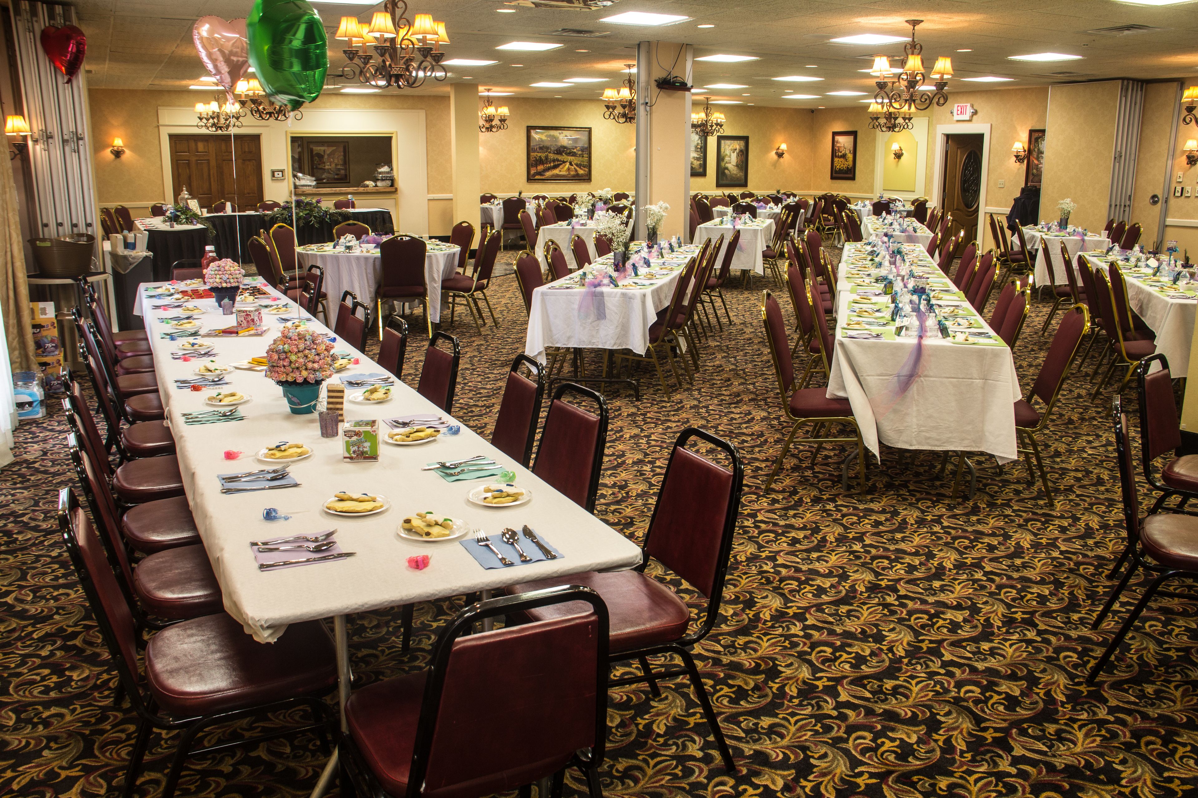 Une salle de banquet avec de nombreuses tables dressées pour le repas, disposées en rangées et entourées de chaises.
