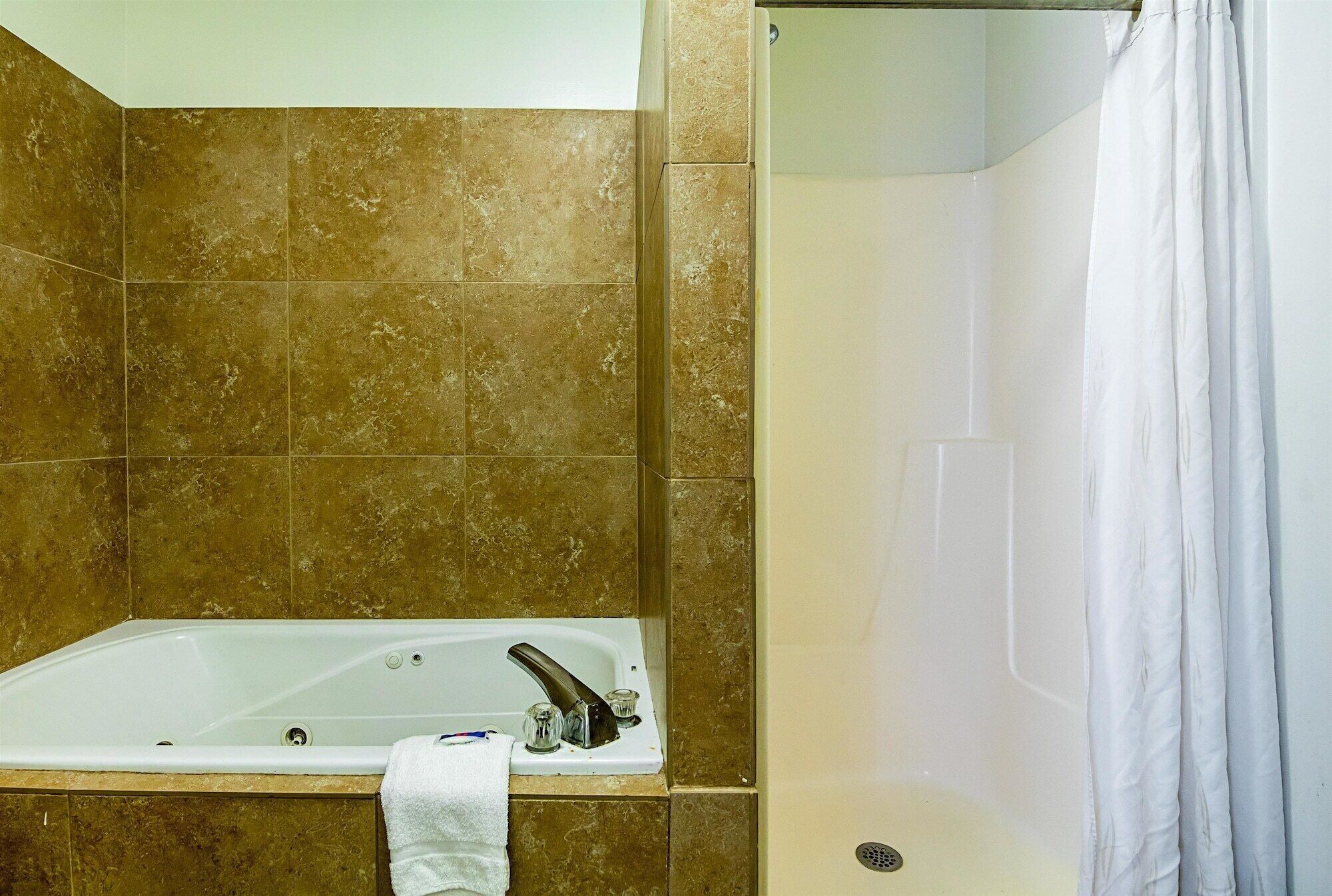 A bathroom with a bathtub, a shower curtain, and tiled walls.