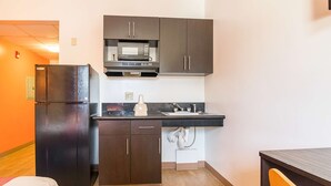 A compact kitchen with dark cabinets, a microwave, and a refrigerator. - Motel 6 Jonesboro, GA (Jonesboro)