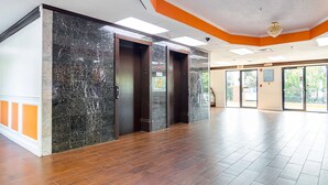 A spacious lobby with marble walls, wooden flooring, and a modern chandelier. - Motel 6 Jonesboro, GA (Jonesboro)