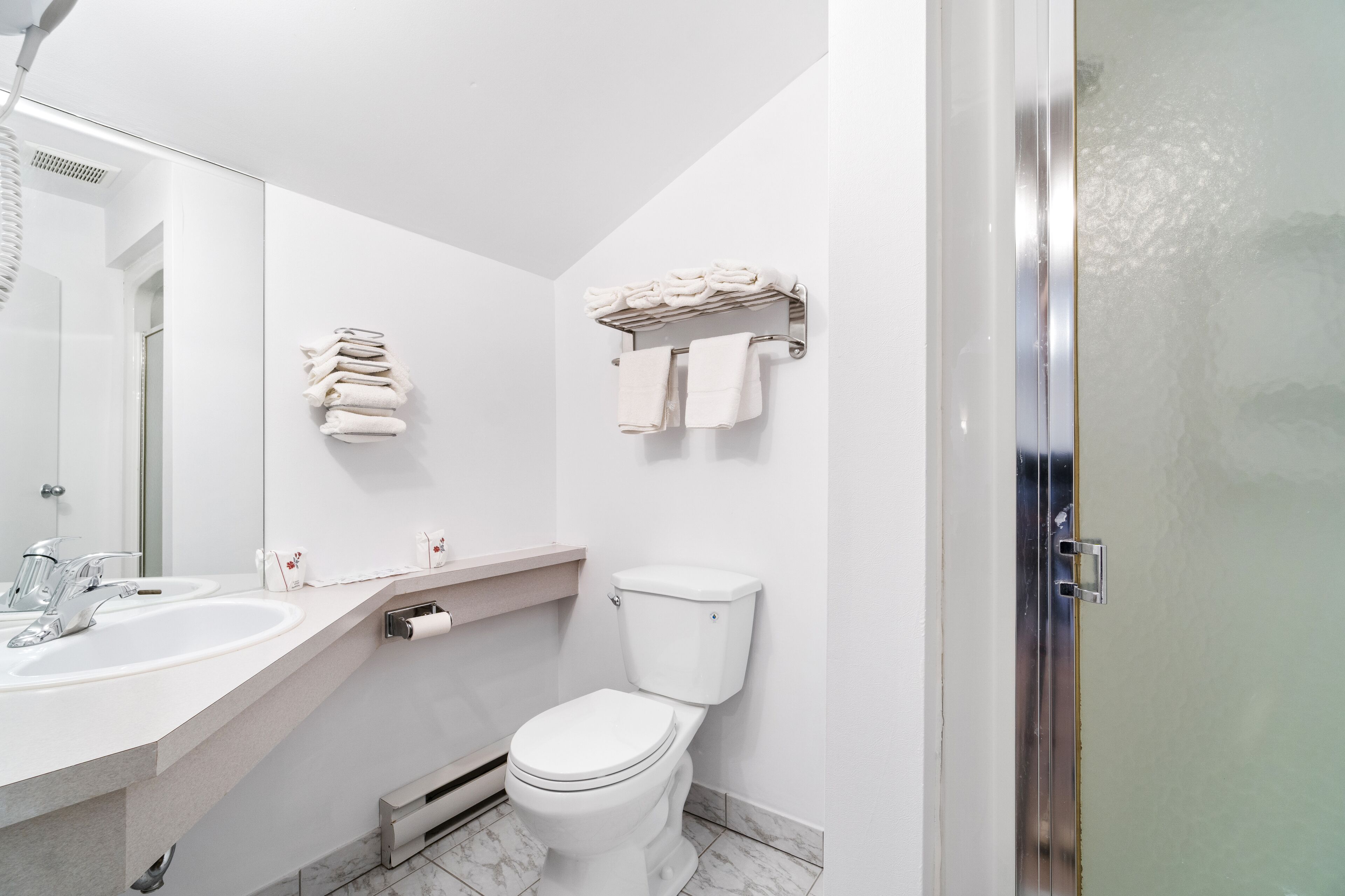 Un baño moderno con inodoro, lavamanos y toallero.