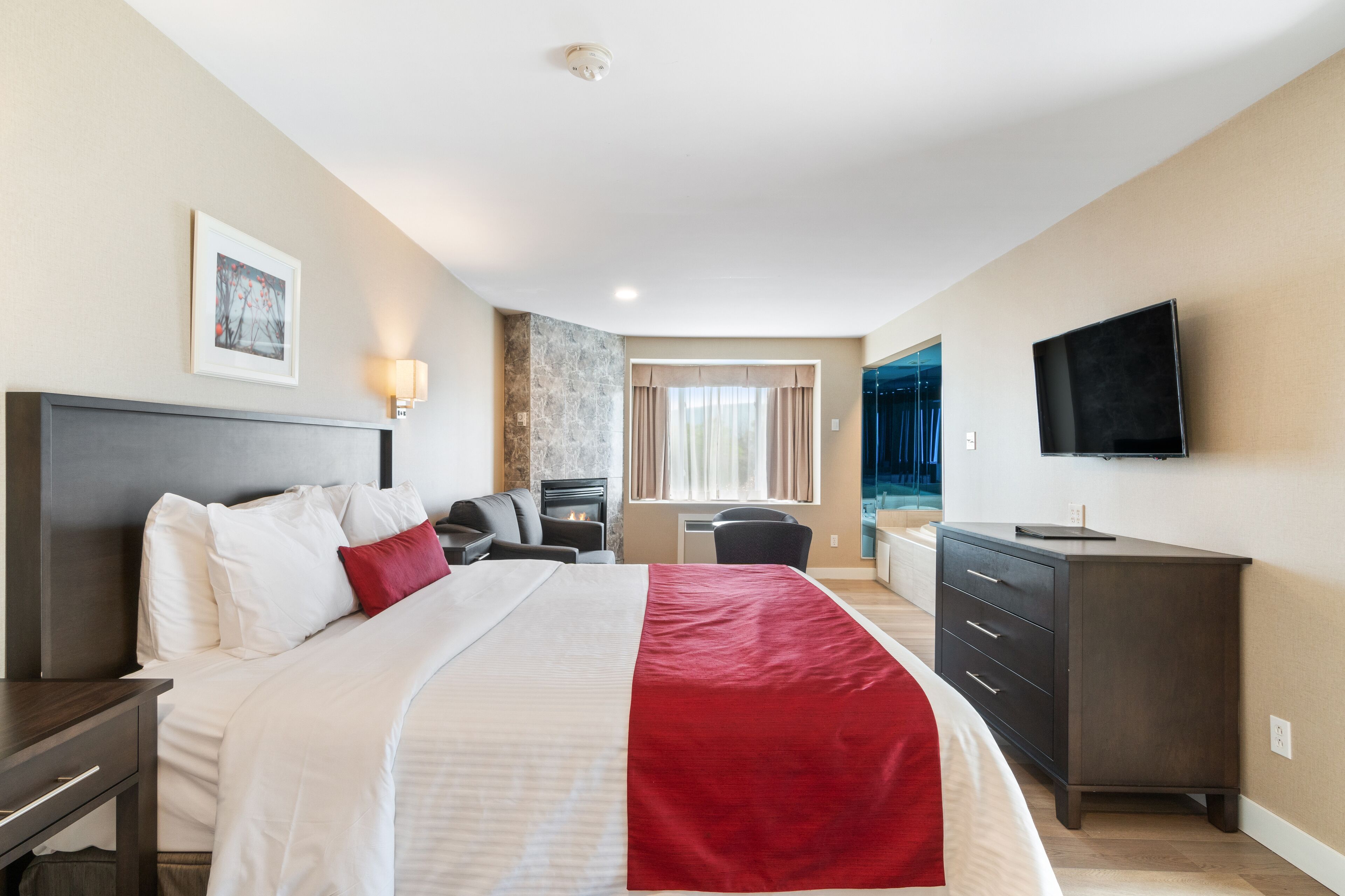 Una habitación de hotel con cama, escritorio, silla, televisión y chimenea.