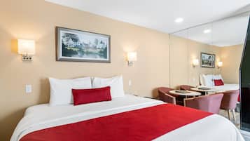 Habitación de hotel con una cama grande, un escritorio y una silla. Hay dos lámparas de pared y un cuadro en la pared.