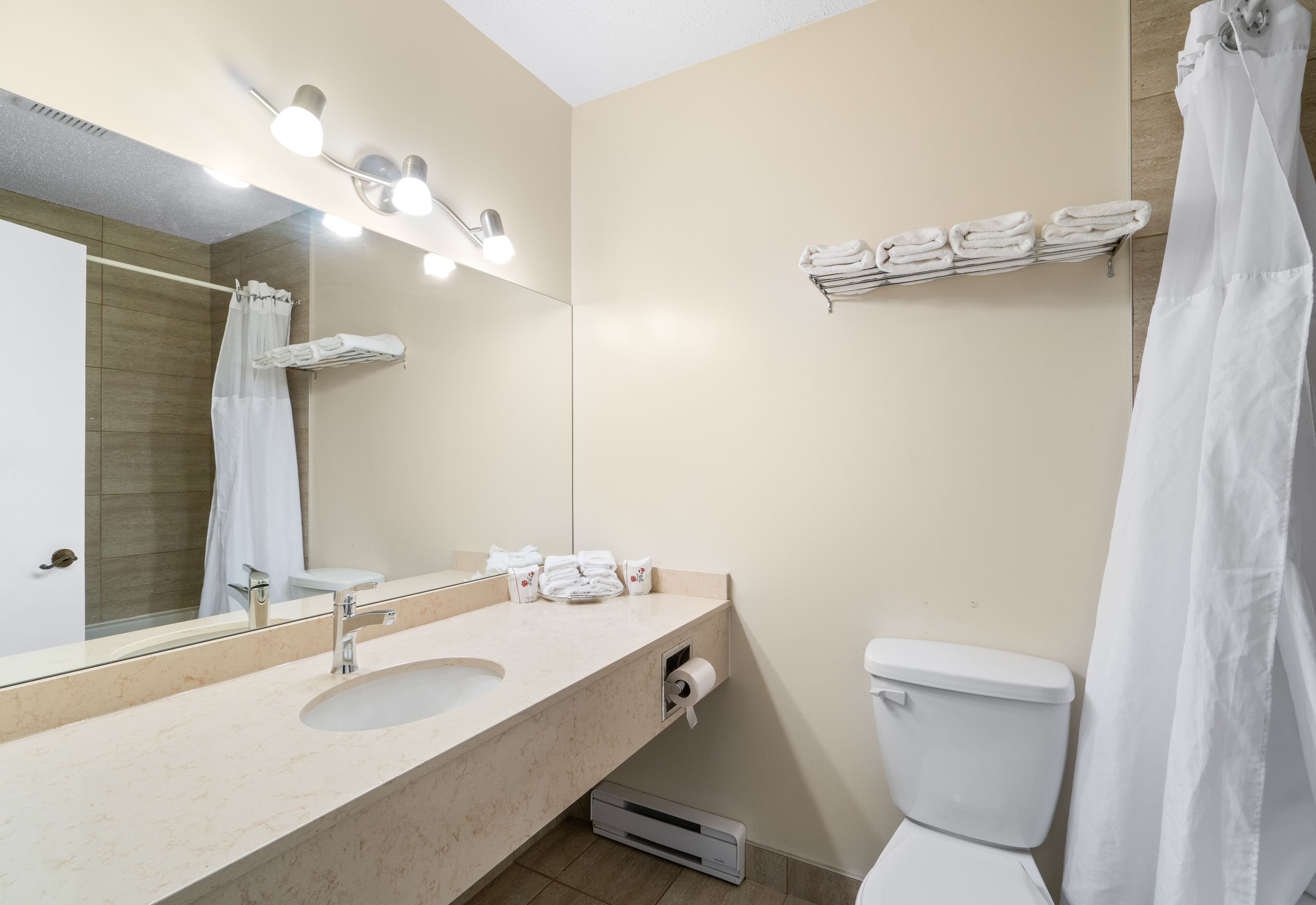Ein Badezimmer mit Waschbecken, Spiegel, Handtuchhalter und Toilette.