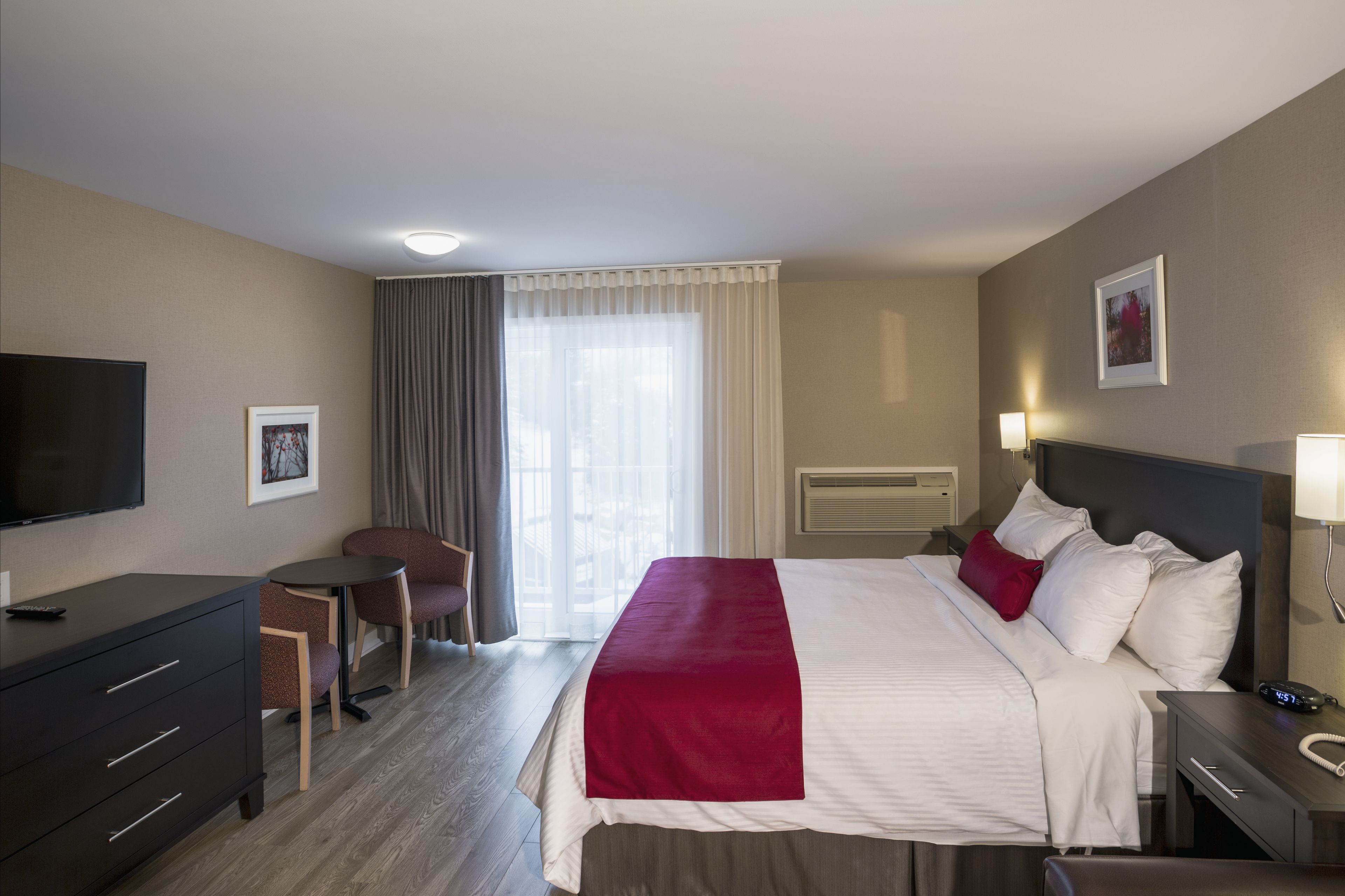 A hotel room with a bed, a desk, a chair, a television, and a window with curtains.