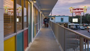 Un motel con paredes exteriores de colores, un pasillo cubierto y un letrero que dice 'Thunderbird Inn'.