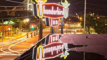Un cartello luminoso al neon per 'Thunderbird Inn', con un ponte sullo sfondo.