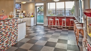 Una cocina moderna con piso a cuadros, una zona de bar colorida y un amplio ventanal con vistas al exterior.