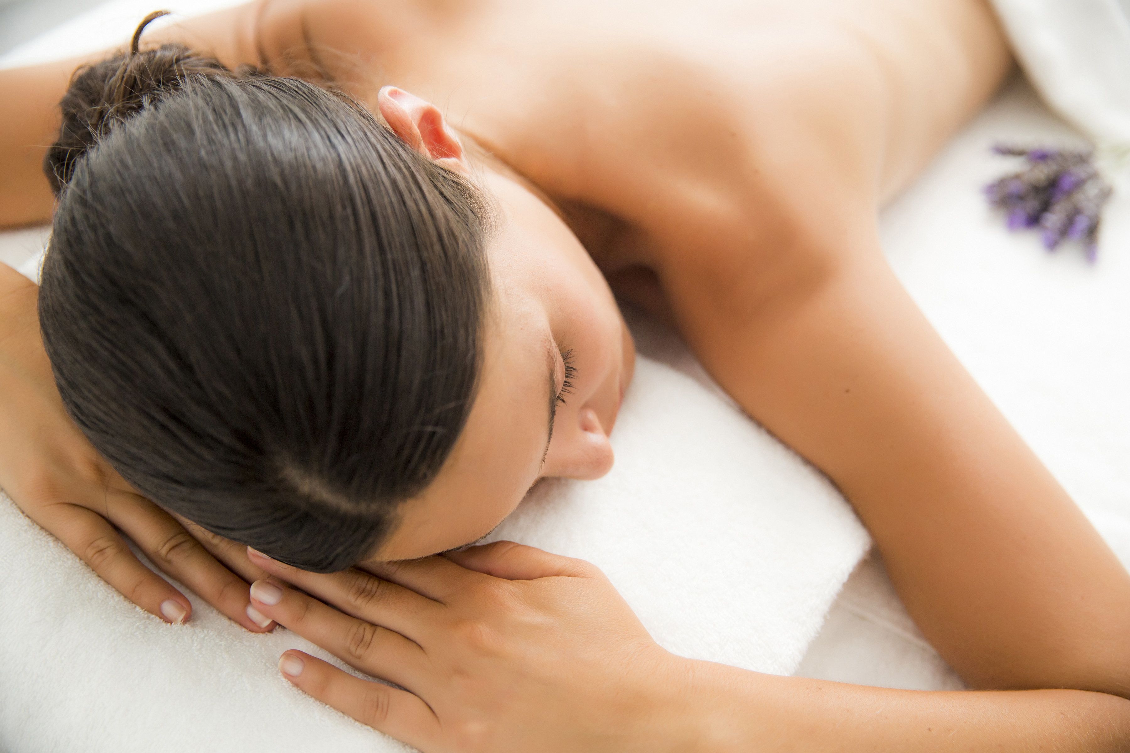 A person lying on a white surface with a white towel.