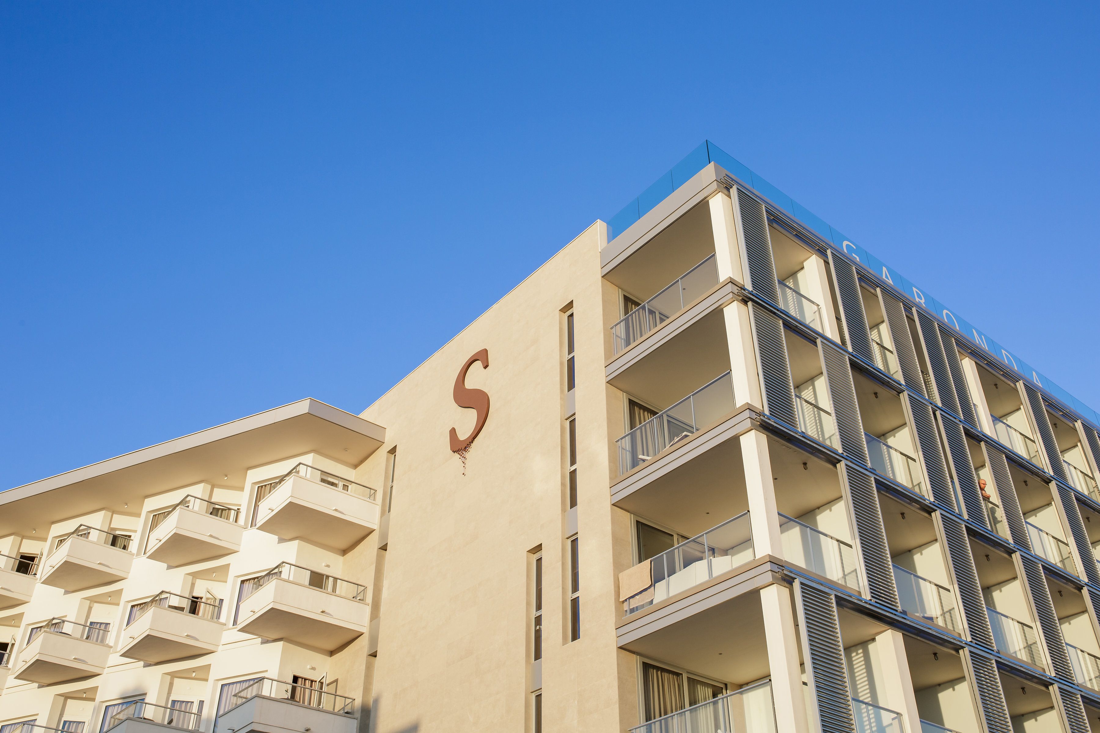 A multi-story hotel with balconies and a prominent 'S' on the facade.