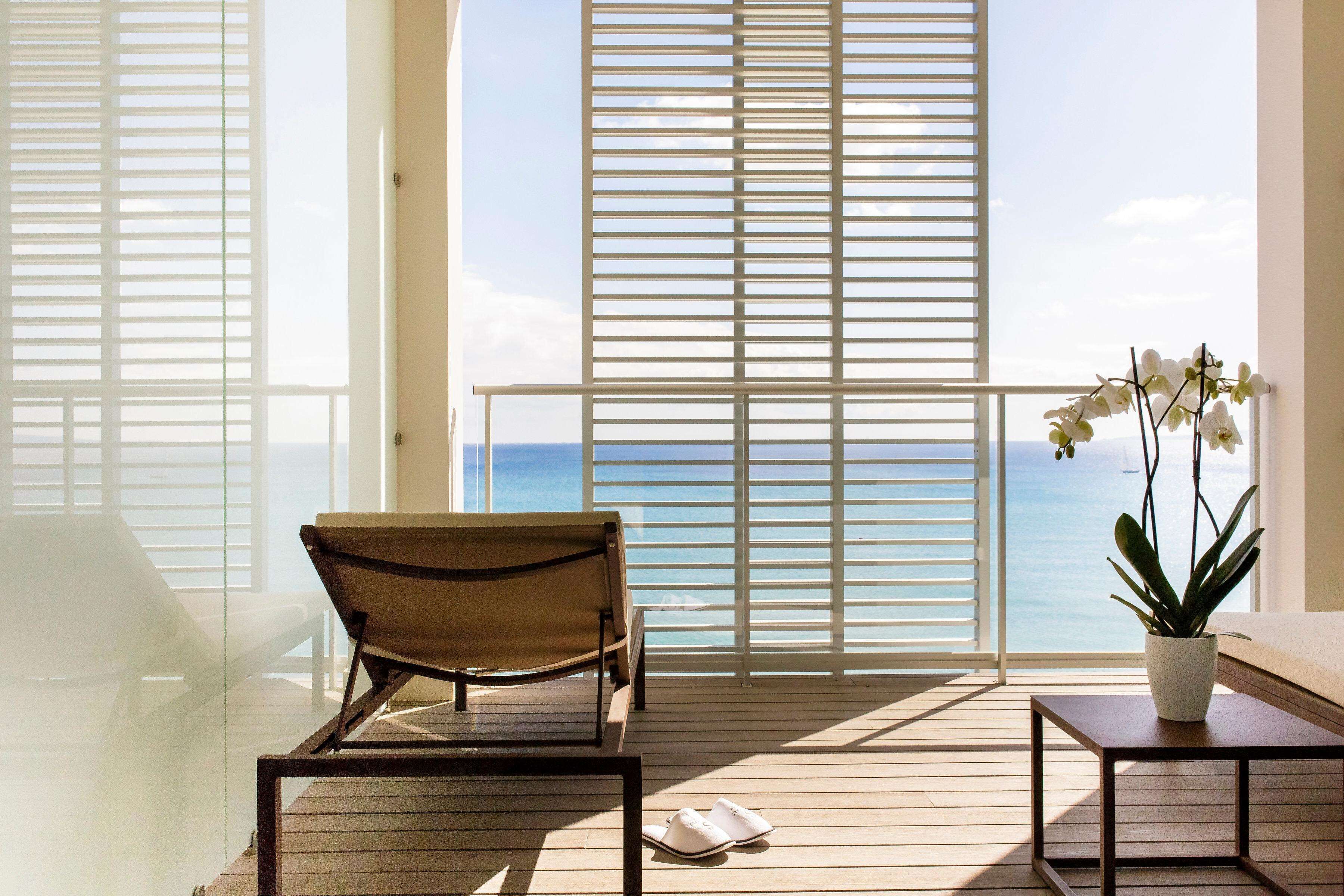 A balcony with a chair, a small table, and a potted plant.
