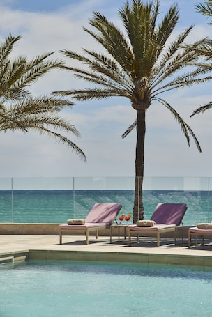 Una piscina techada, una piscina al aire libre, sombrillas