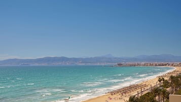 Una playa con una torre de salvavidas, sombrillas y gente.