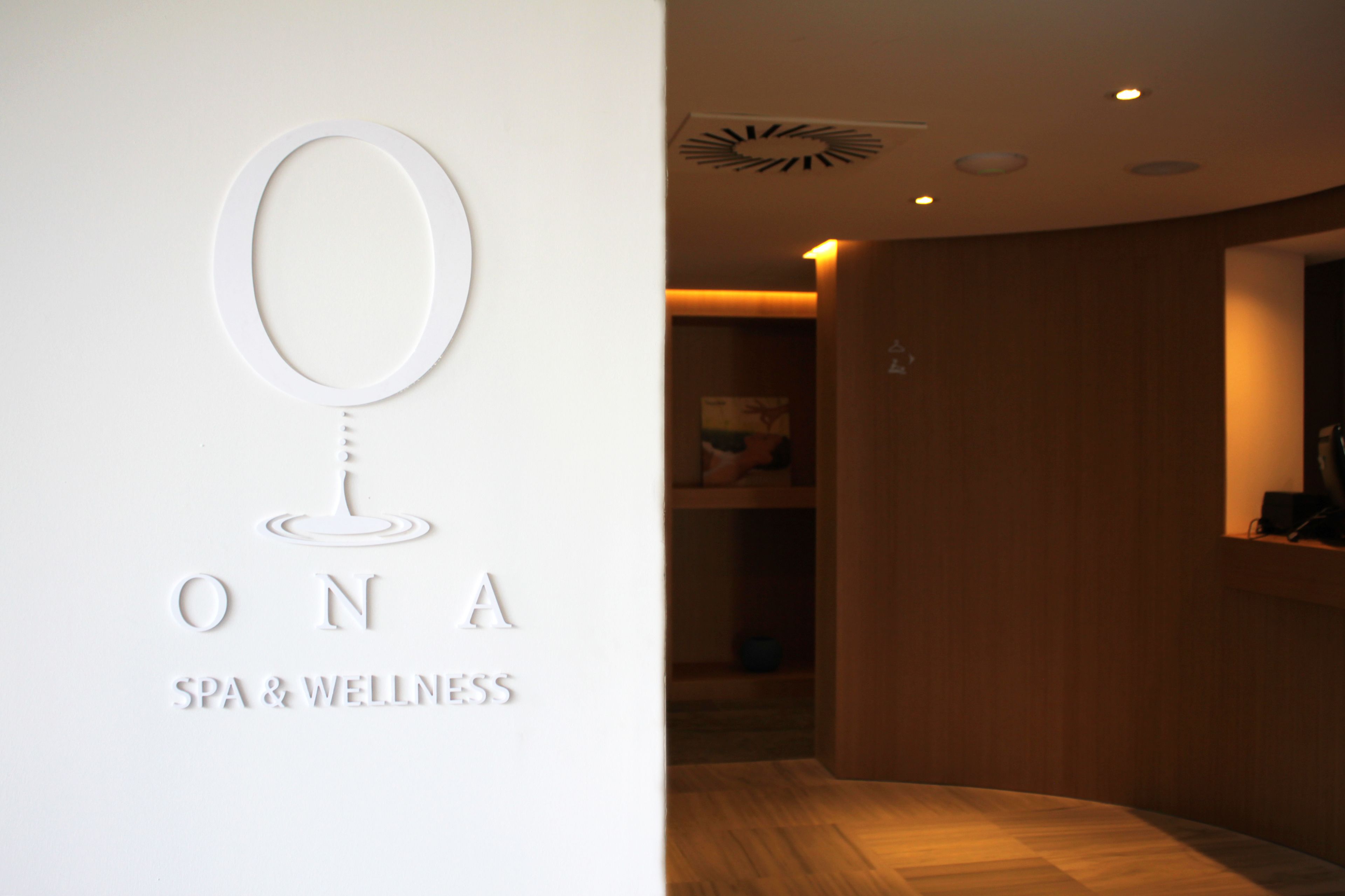 A spa and wellness center with a minimalist design, featuring a reception area with wooden paneling and a modern ceiling light fixture.