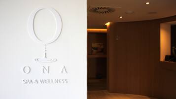 A spa and wellness center with a minimalist design, featuring a reception area with wooden paneling and a modern ceiling light fixture.