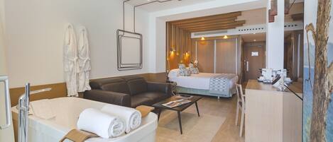 Una habitación de hotel moderna con una bañera, un sofá, una cama y un escritorio.
