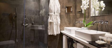Un baño moderno con cabina de ducha de vidrio, un lavabo blanco y un espejo grande.