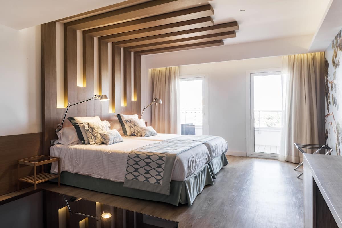 A modern bedroom with a large bed, bedside tables, and a desk.