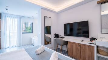 Habitación de hotel moderna con una cama bien hecha, un escritorio con silla, un televisor de pantalla plana y un espejo grande.