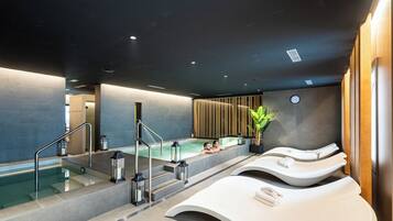 Relax in a serene spa area with a large hot tub, lounge chairs, and a clock.
