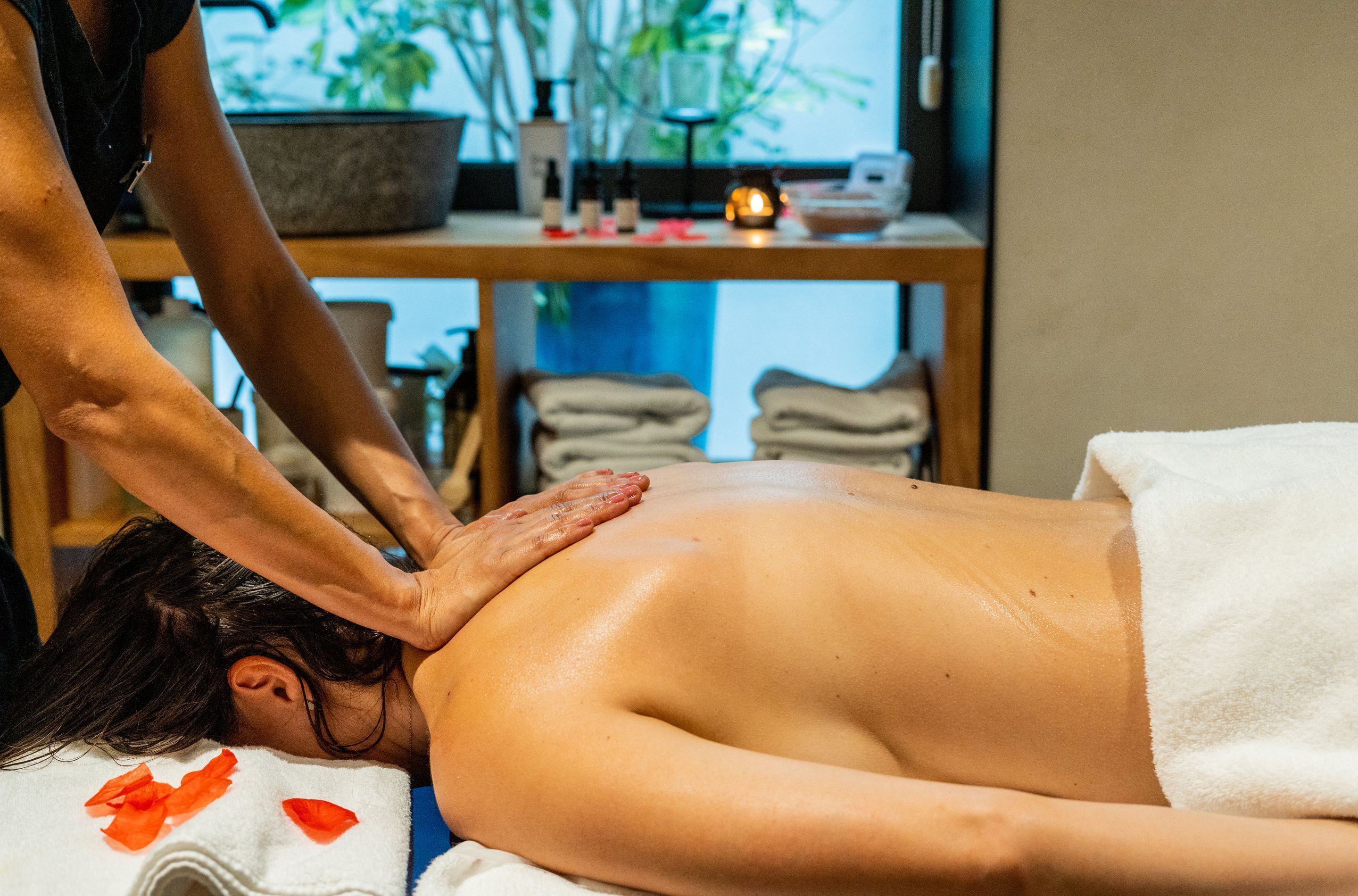 Sesión de masajes en un spa, con una mesa de madera, velas y toallas.