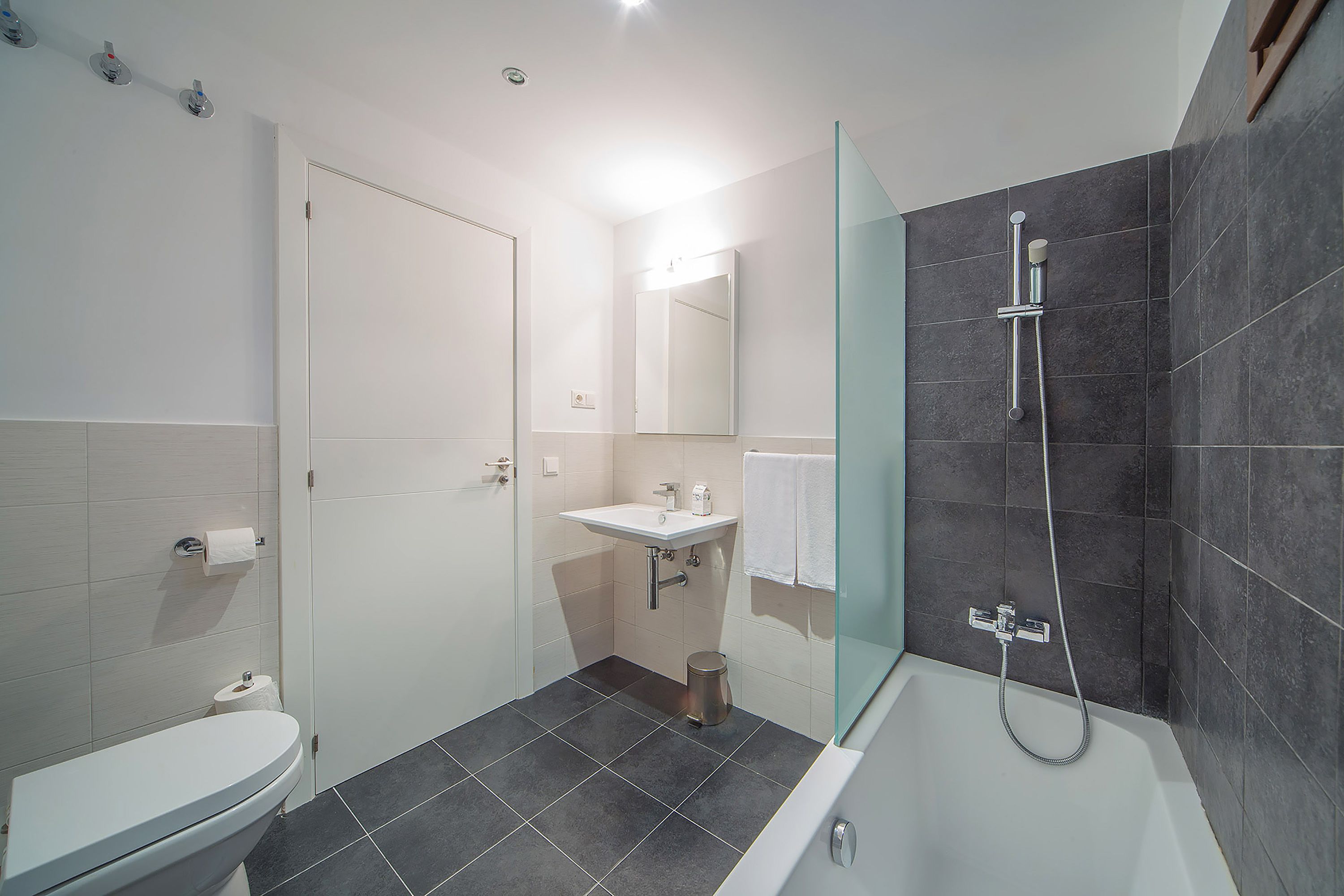 A modern bathroom with a toilet, sink, and shower.