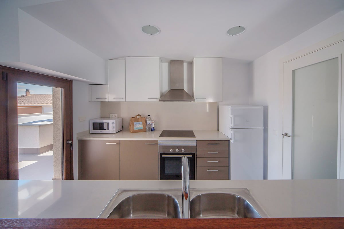 A modern kitchen with white cabinets, a microwave, a stove, and a refrigerator.
