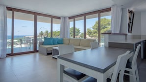 Ein modernes Wohnzimmer mit Essbereich, großen Fenstern und Blick aufs Meer.