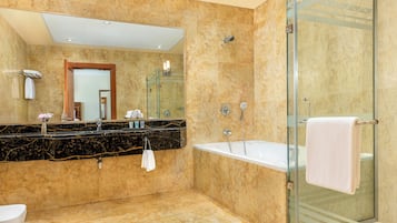 Un baño moderno con piso de mármol, un espejo grande, una bañera y una ducha con paredes de vidrio.