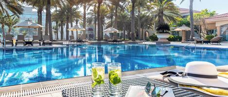 A poolside area with lounge chairs, umbrellas, and a magazine on a table.