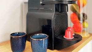 A coffee maker with two blue cups on a wooden surface.