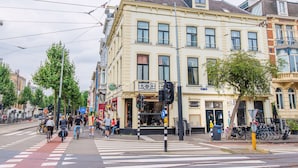 A street corner with a café, bicycles, and pedestrians.