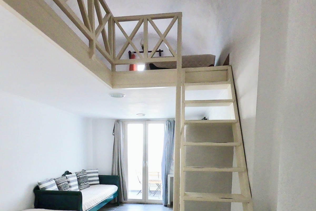 Un dormitorio con una cama litera, un escritorio y una escalera.