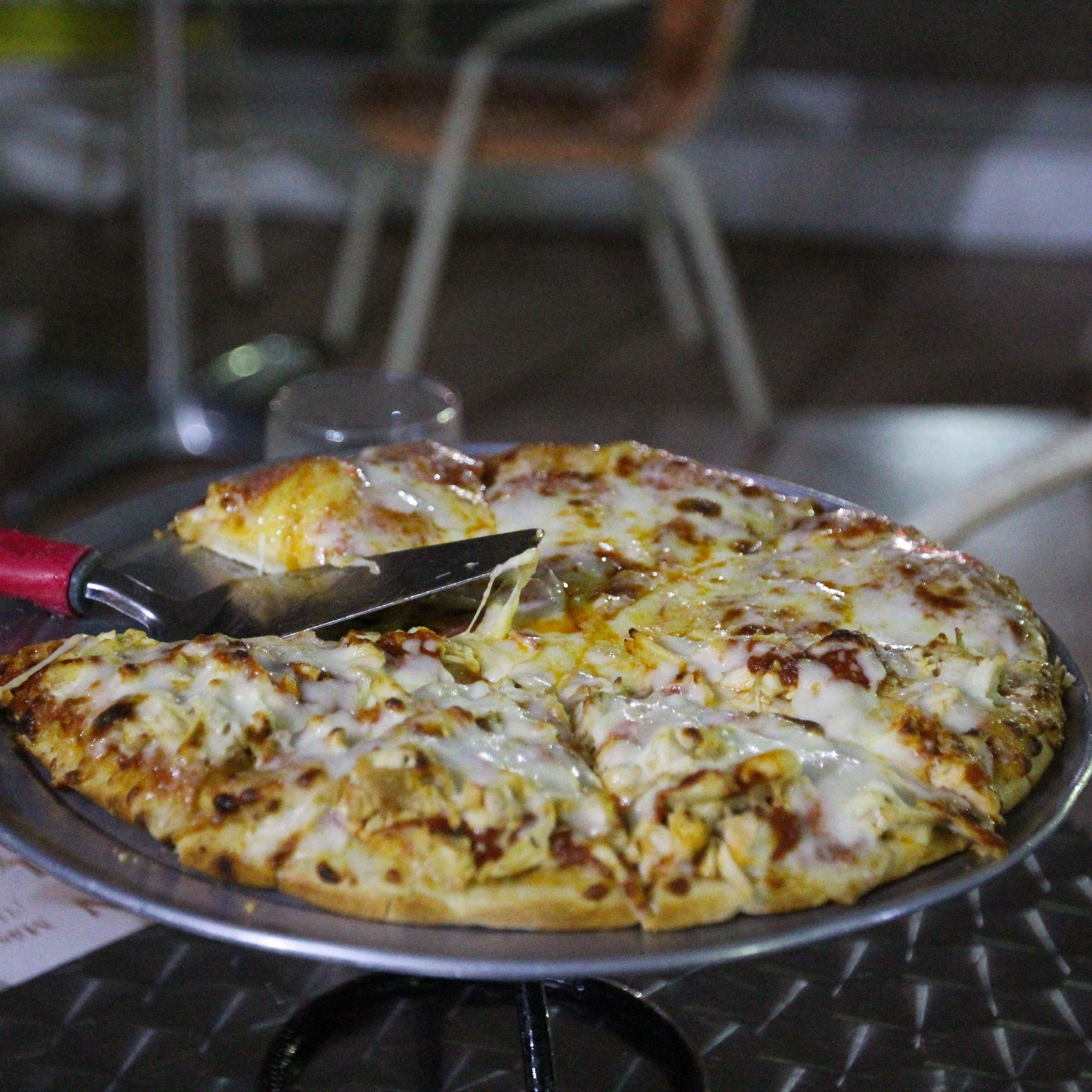 En pizza på en metalbakke med en pizzaskærer.