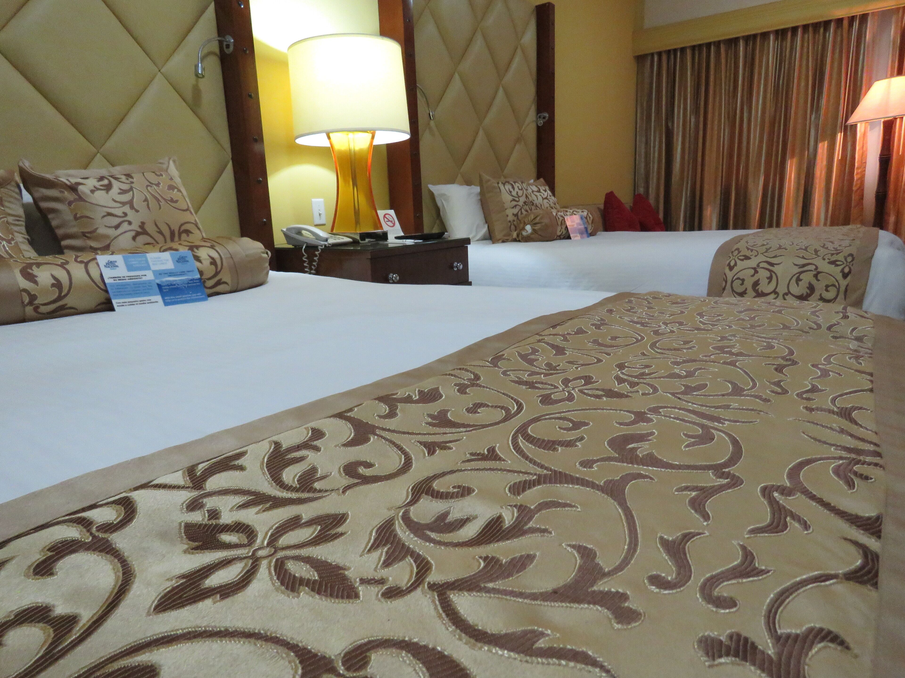 Habitación de hotel con dos camas, un escritorio con teléfono y una lámpara.