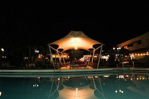 Una piscina al aire libre, sombrillas, sillones reclinables de piscina